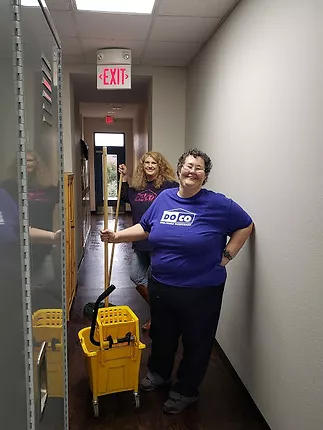 two doco employees cleaning a hallway